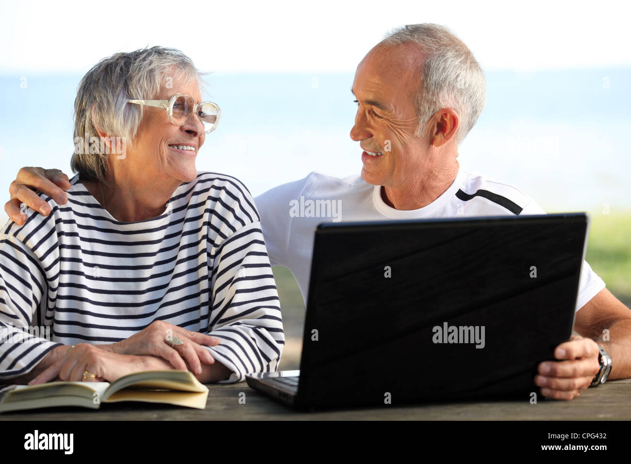 Senior couple in the garden with laptop and book Stock Photo