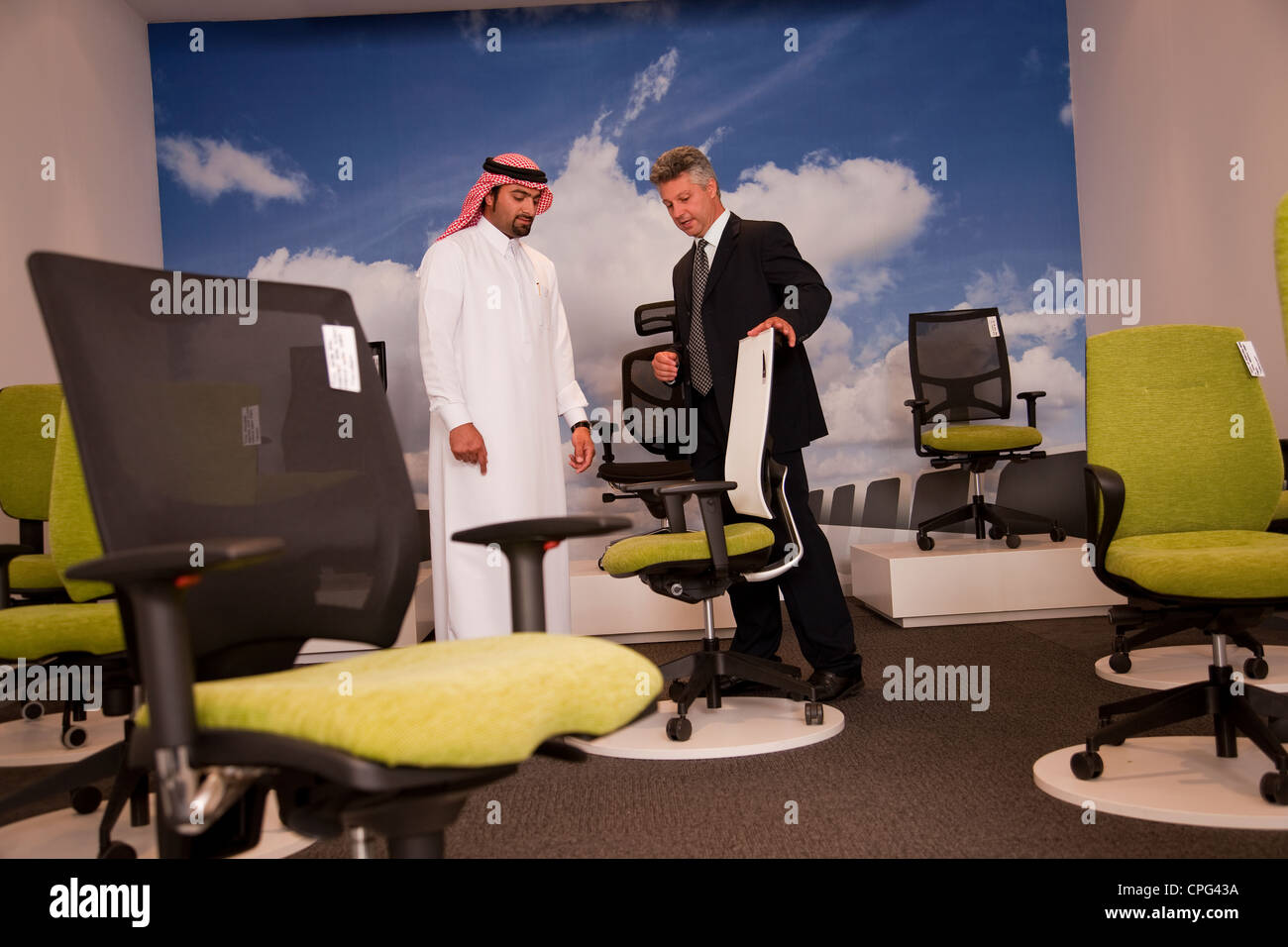Salesman assisting arab man shopping for office chairs in furniture store. Stock Photo
