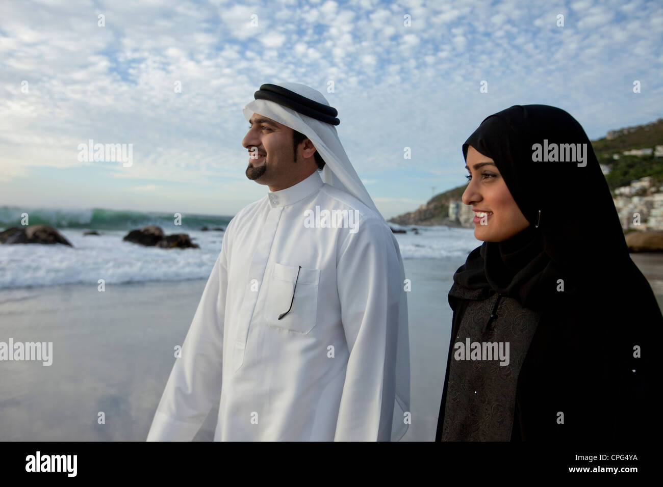 Arab couple standing by the beach, smiling. Stock Photo