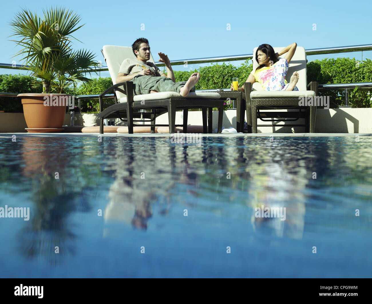 Two couples sitting by swimming pool hi-res stock photography and ...