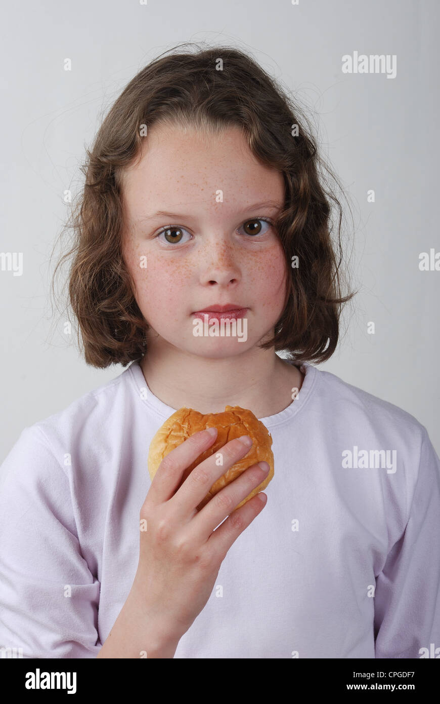 A young girl eating a bun Stock Photo