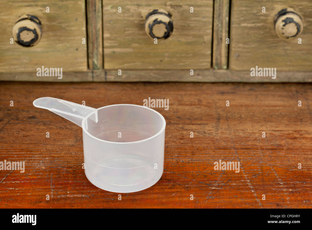 empty plastic measuring cup on a grunge wooden counter with drawer cabinet Stock Photo