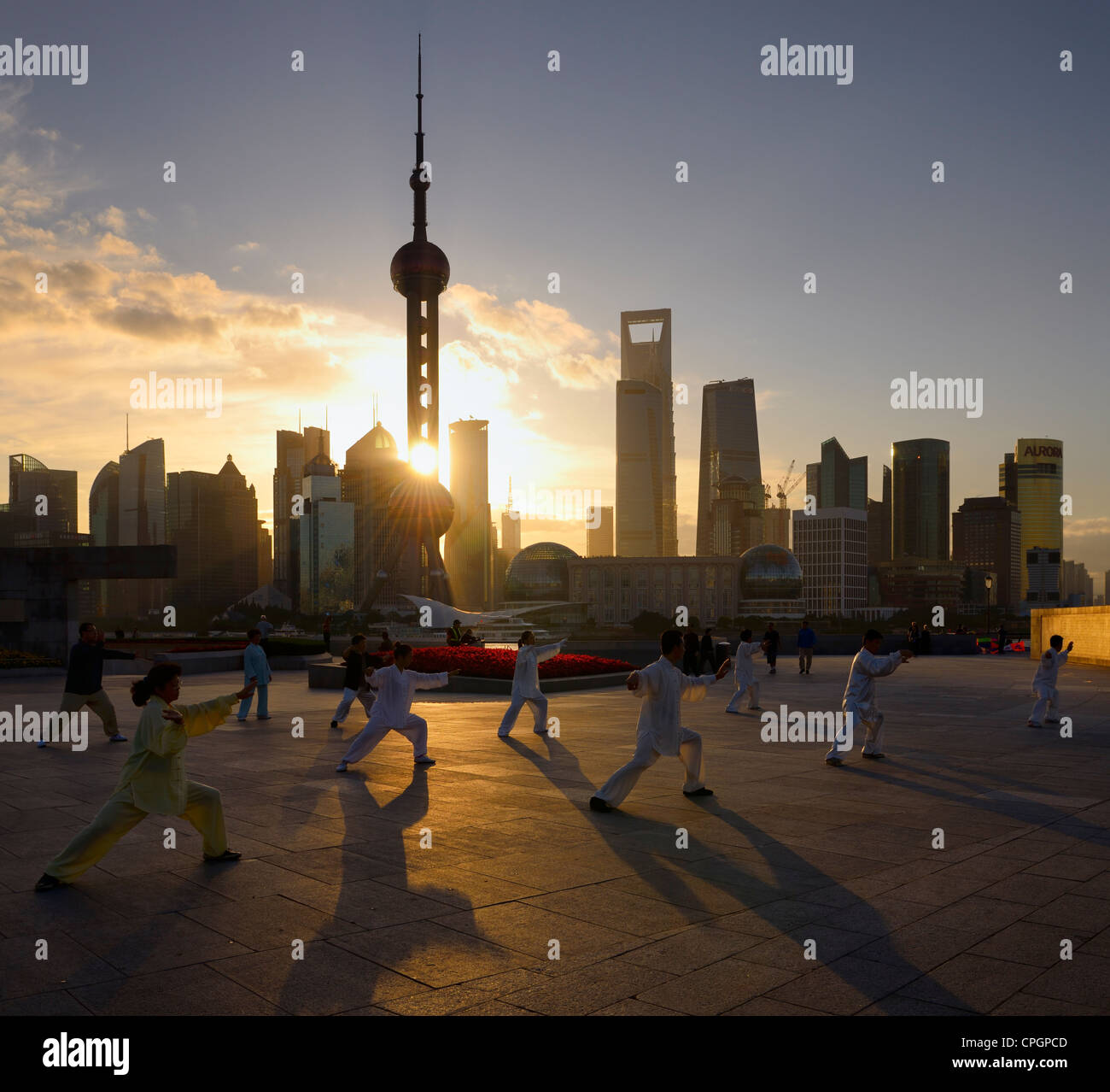 Sunrise shining through the Oriental Pearl Tower onto Tai Chi group exercising on the Bund Shanghai China Stock Photo