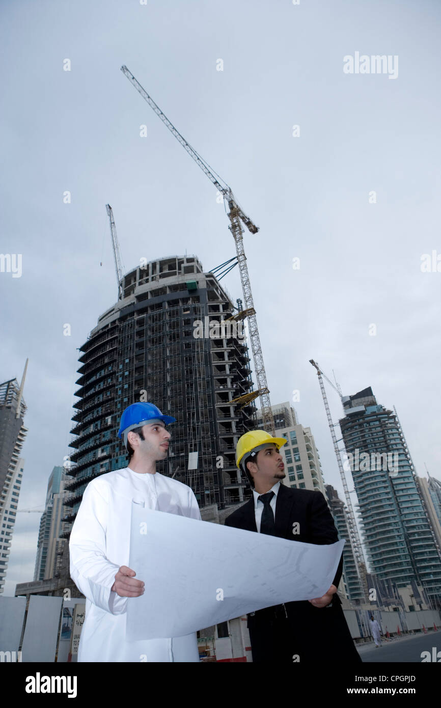 Businessmen holding blueprint at construction site Stock Photo - Alamy