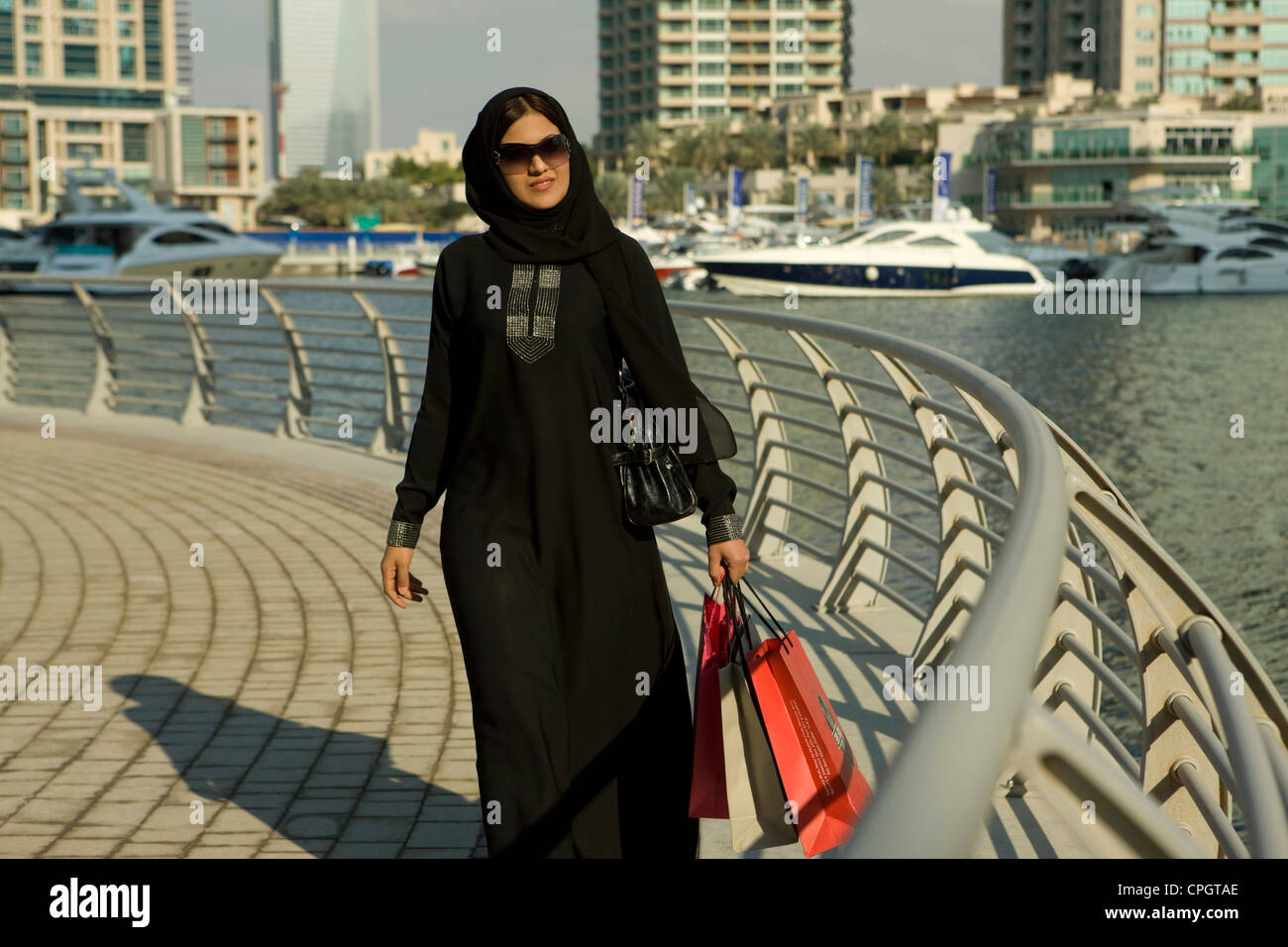 Arab woman with shopping bags, walking at Dubai Marina, UAE Stock Photo