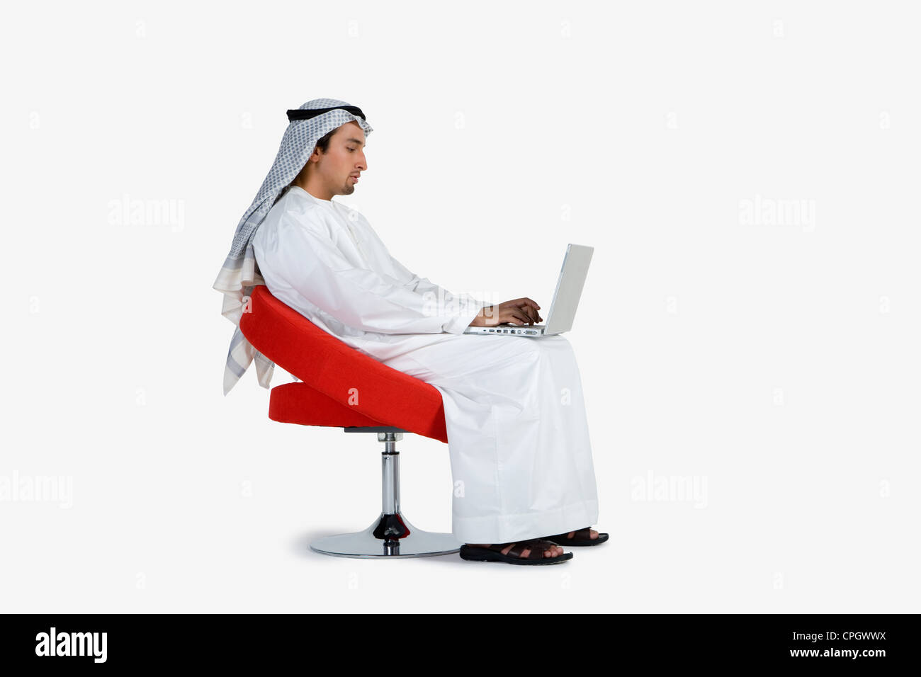 Young man sitting on chair, using laptop Stock Photo