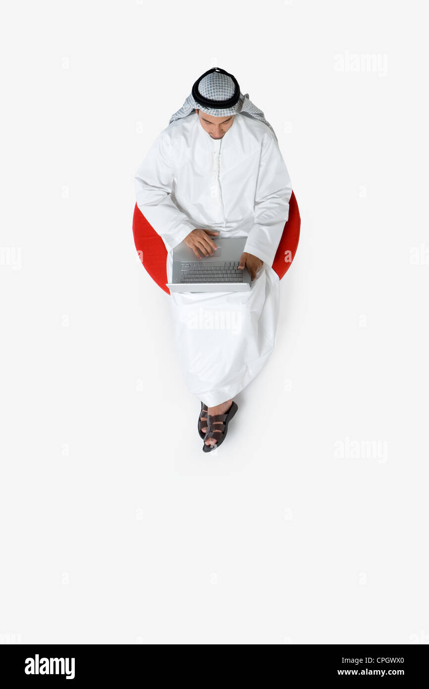 Young man sitting on chair, using laptop, top view Stock Photo