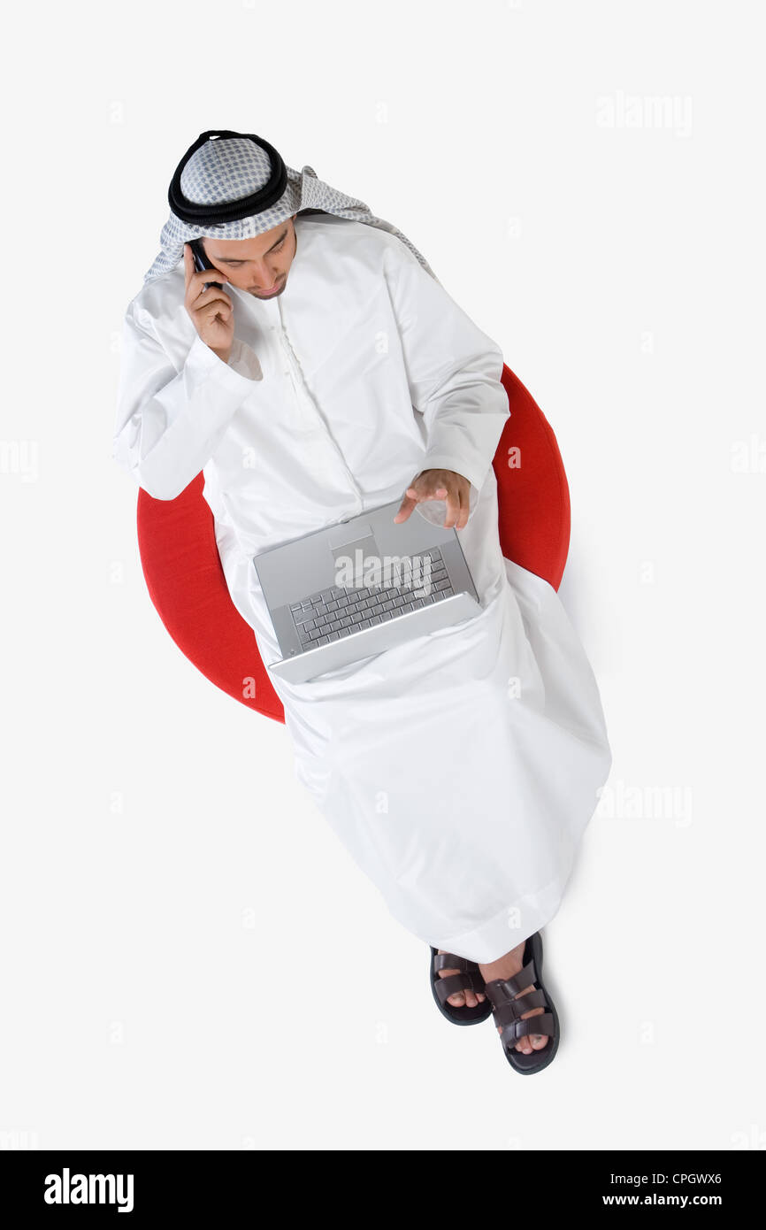 Young man on the phone, using laptop, elevated view Stock Photo