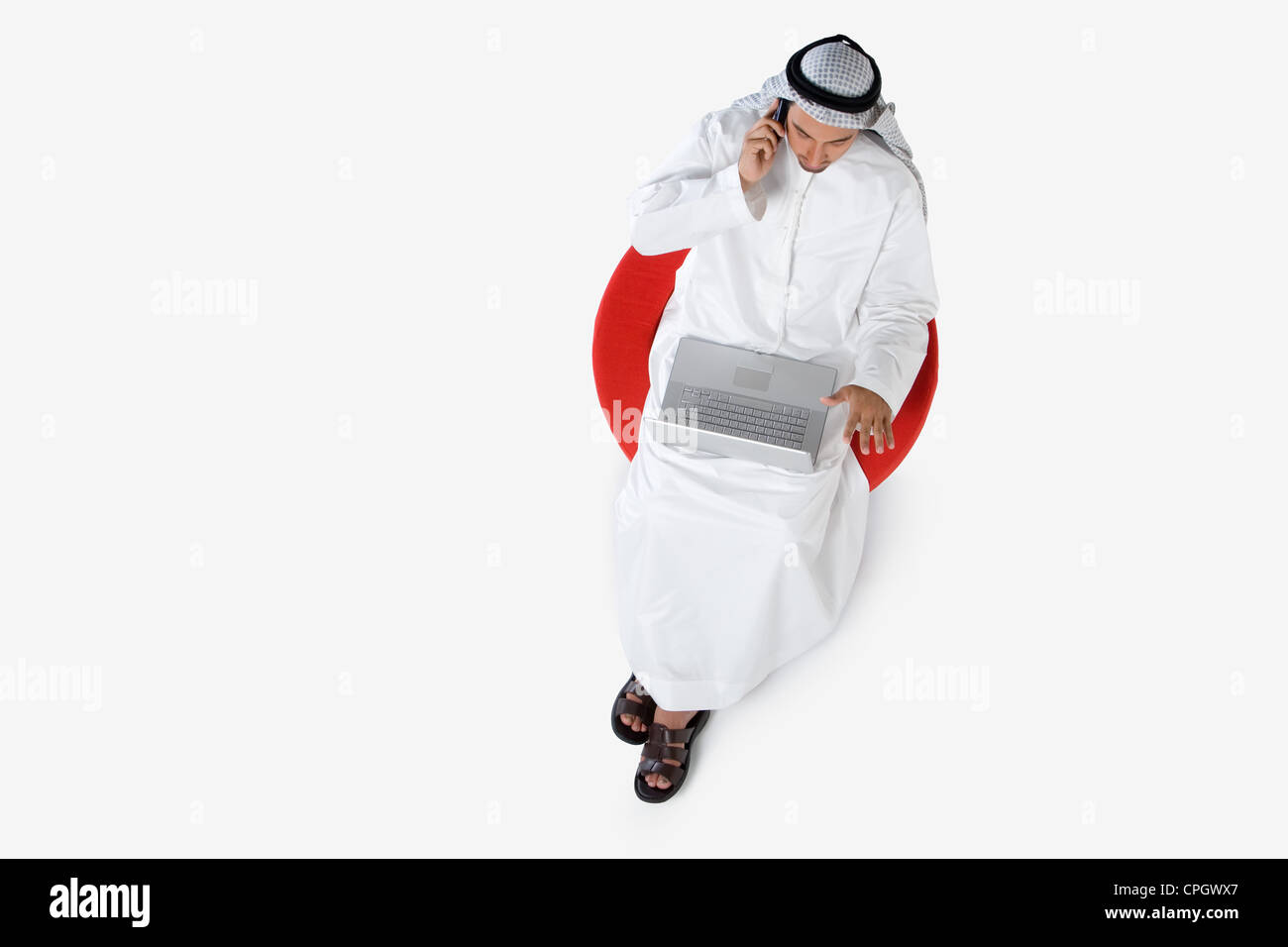 Young man on the phone, using laptop, elevated view Stock Photo