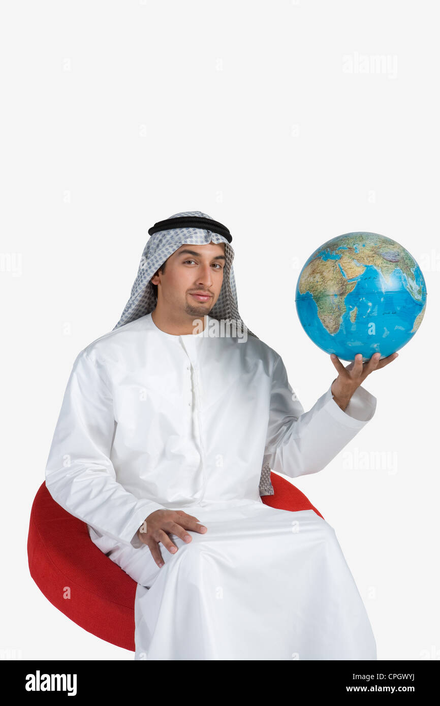 Young man sitting on chair, holding globe, portrait Stock Photo