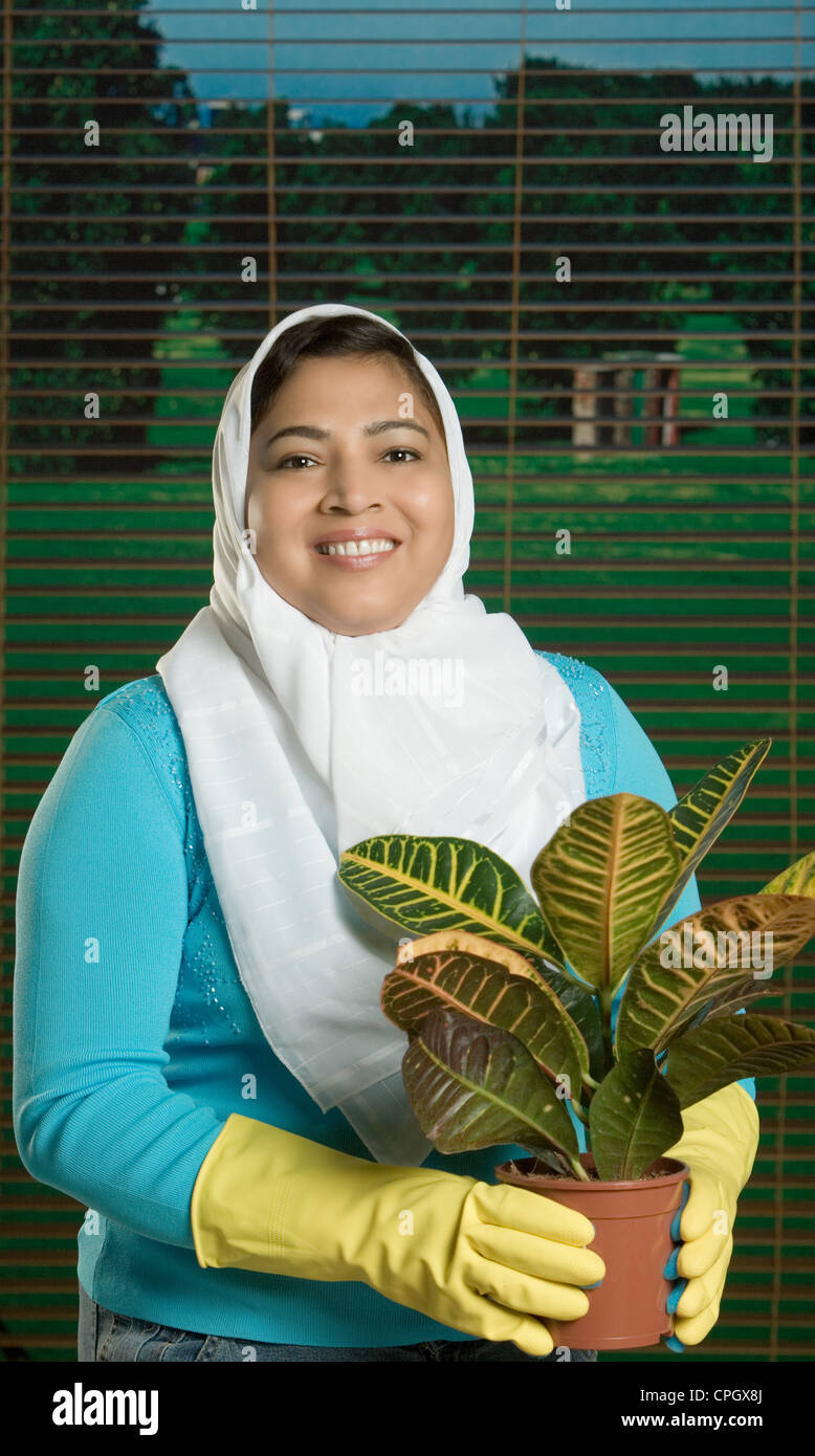 Mid adult woman holding potted plant, smiling, portrait Stock Photo - Alamy
