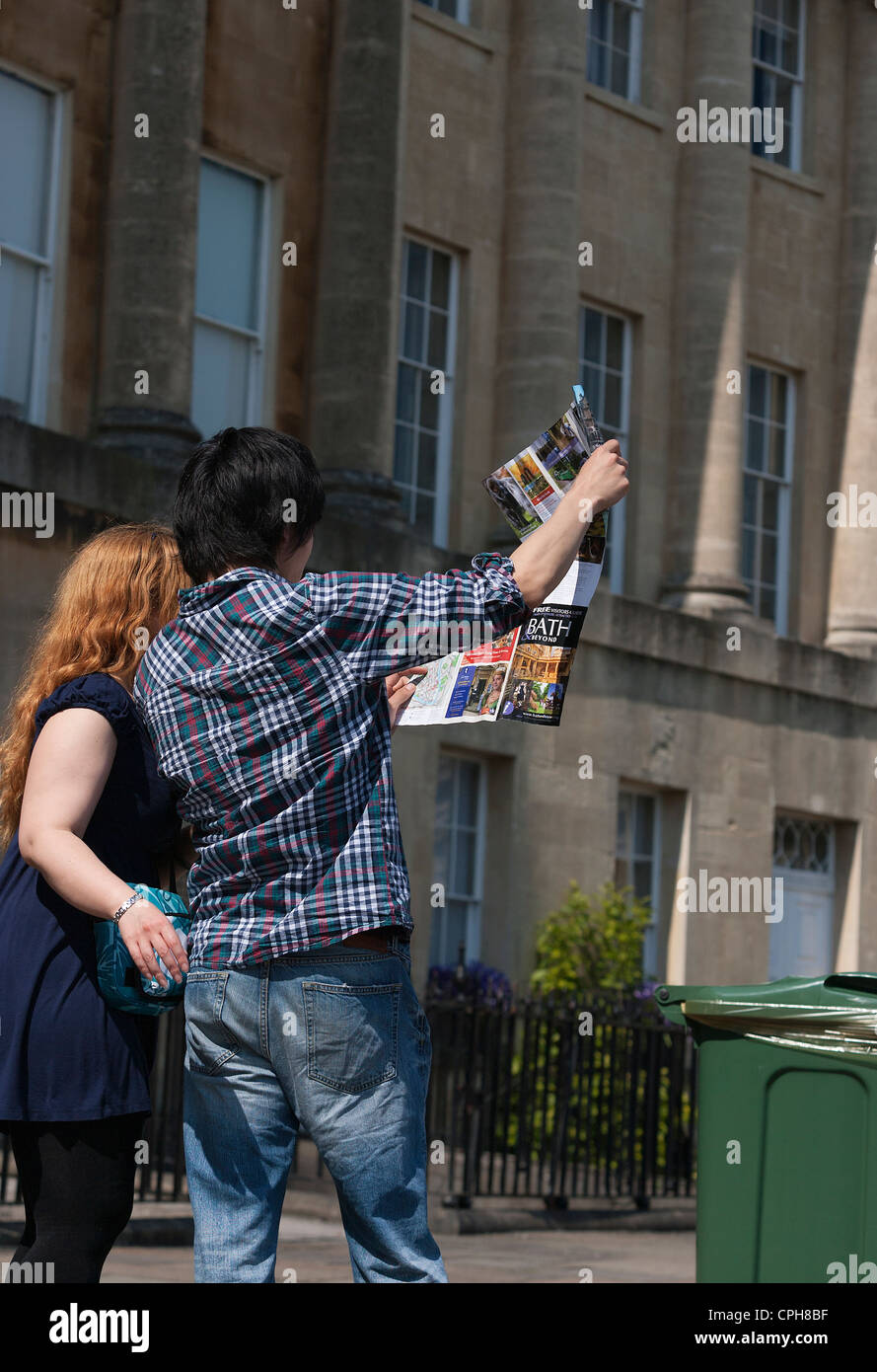 Two visitors to Bath look at a map of the city as they stand in Bath's famous Royal Crescent. Bath, Somerset, England, UK. Stock Photo