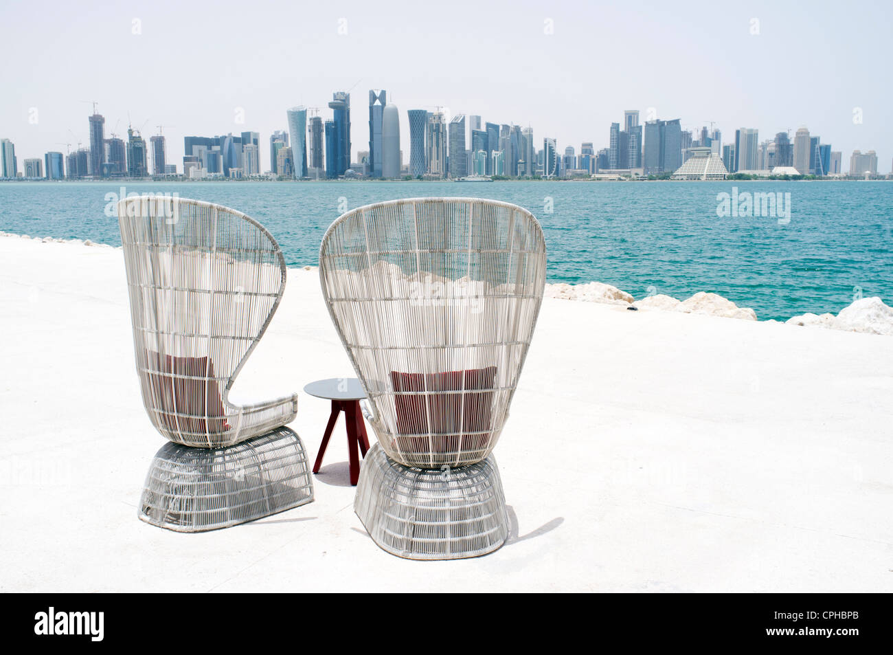 Modern outdoor seating at waterfront cafe with view of skyline of Doha ...