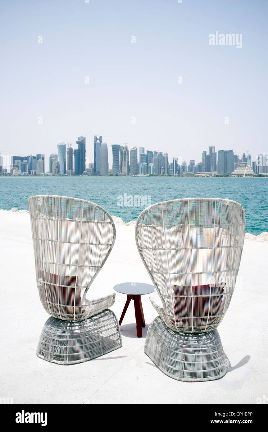 Modern outdoor seating at waterfront cafe with view of skyline of Doha ...