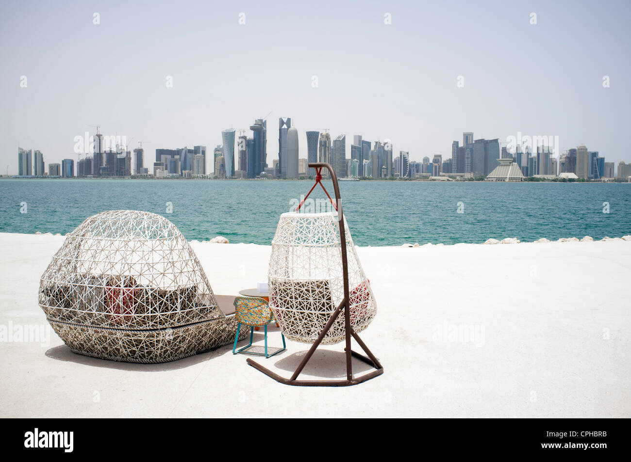 Modern outdoor seating at waterfront cafe with view of skyline of Doha ...