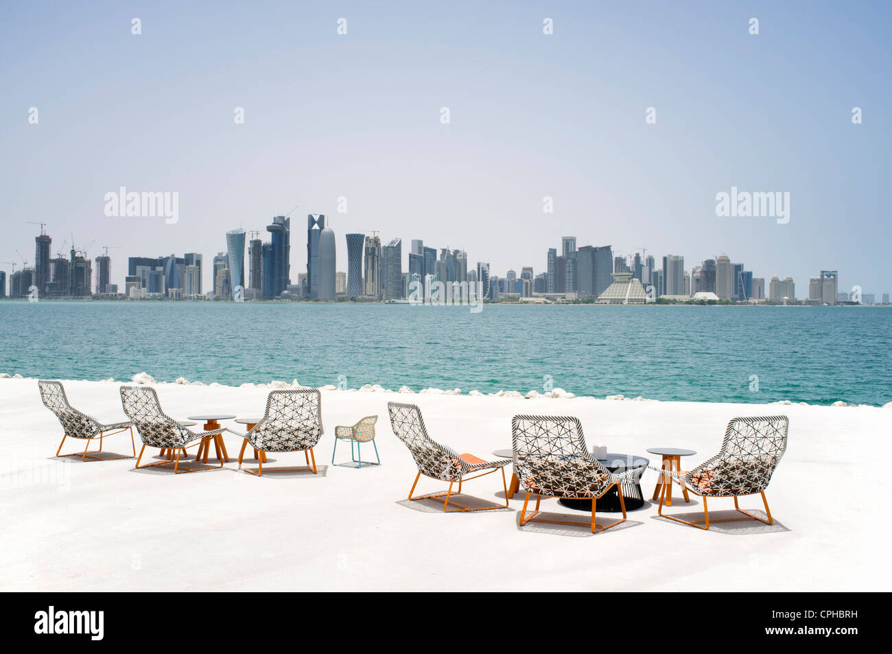 Modern outdoor seating at waterfront cafe with view of skyline of Doha in Qatar Stock Photo