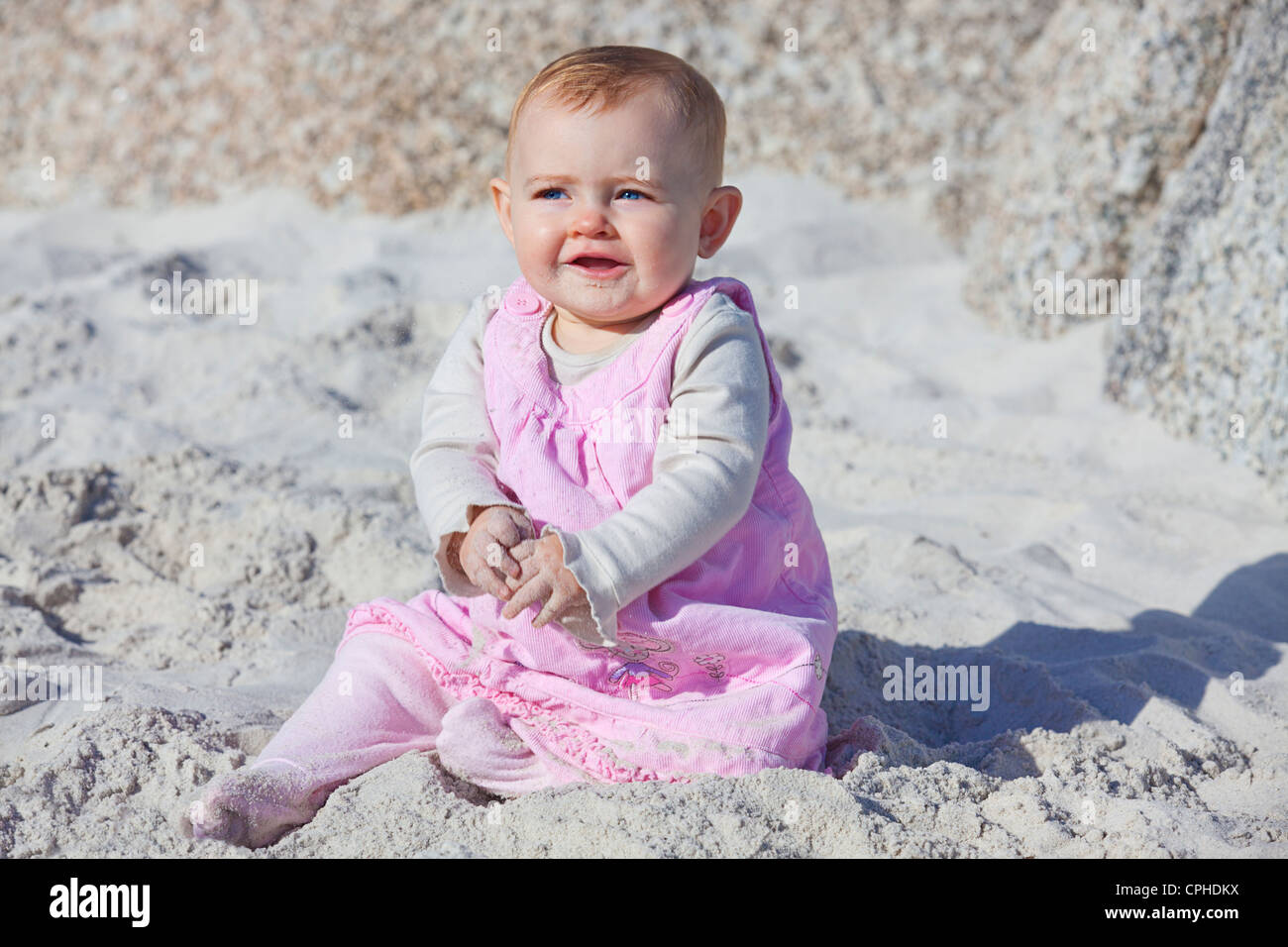 Young 8 month old baby girl on the beach smiling Stock Photo