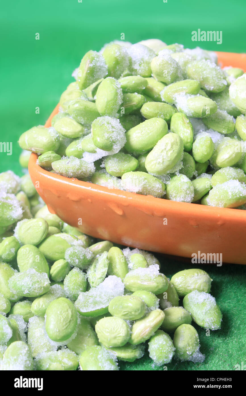 Frozen edamame also known as soybeans in a bowl on a green background