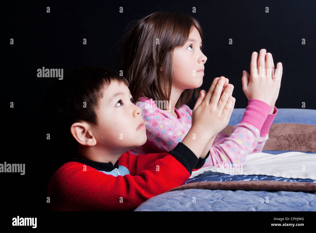 A brother and sister say their prayers just before bedtime Stock Photo