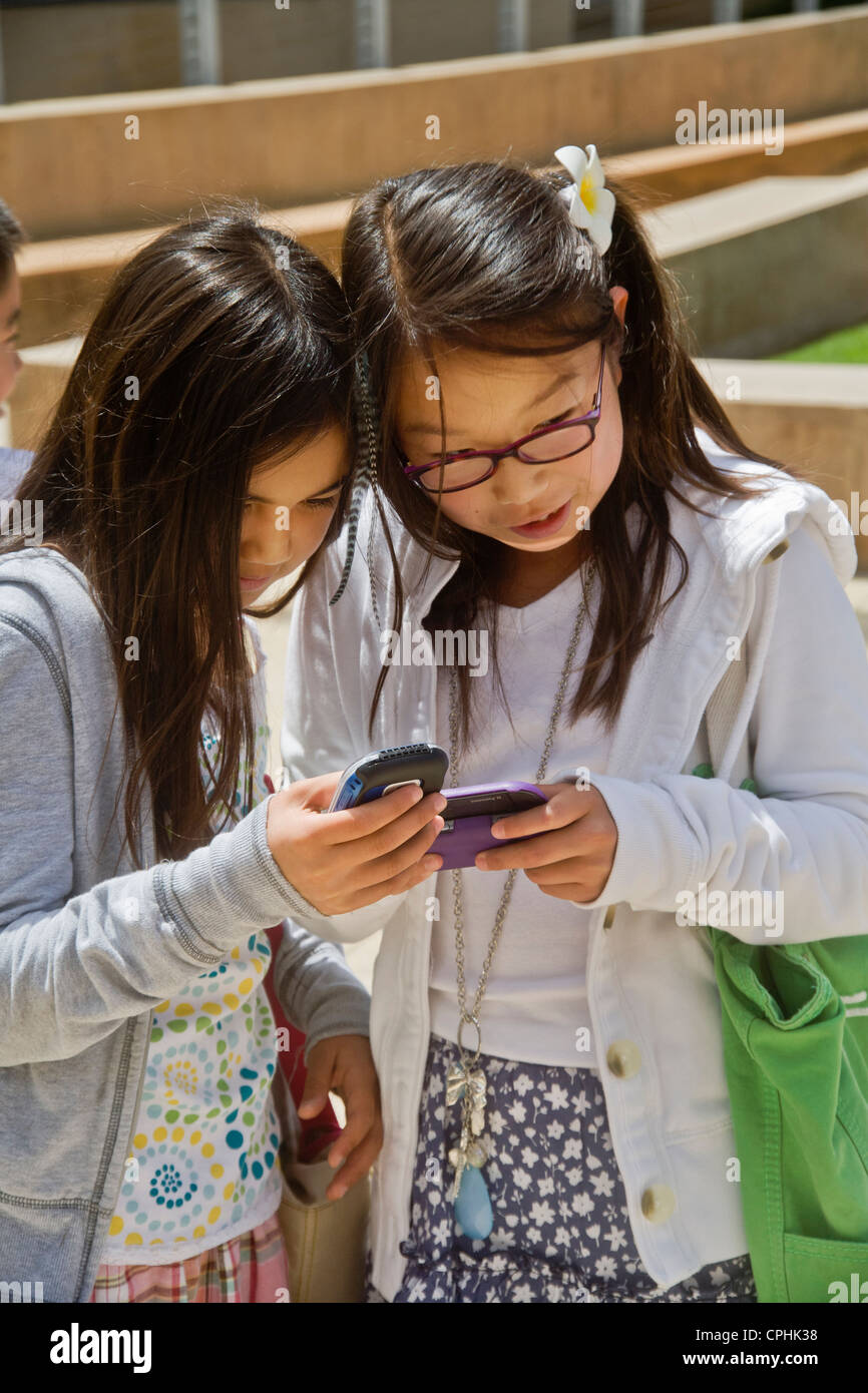 Two preteen girls, one Asian and one Caucasian compare blogs on their cell phones in Irvine, CA. Stock Photo