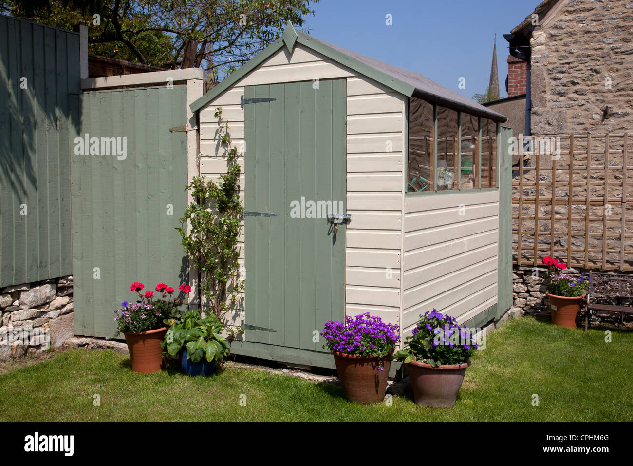 painted garden shed in small English town house garden with pots of flowers Stock Photo