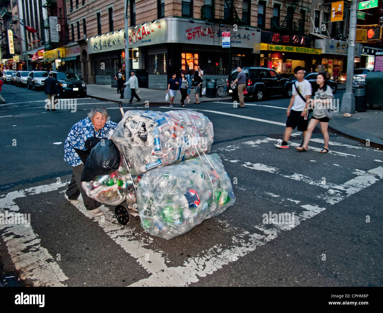 A poor elderly Chinese woman collects cans and bottles for deposit money in New York City's Chinatown Stock Photo