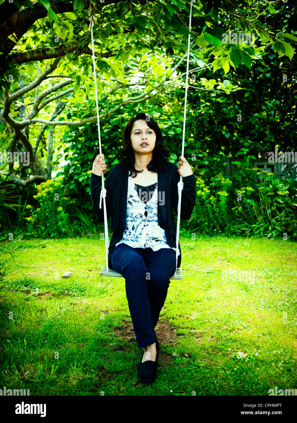 Punjabi woman on swing in garden Stock Photo