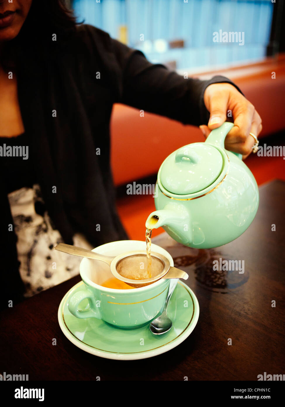 Woman pours cup of tea in cafe. Stock Photo