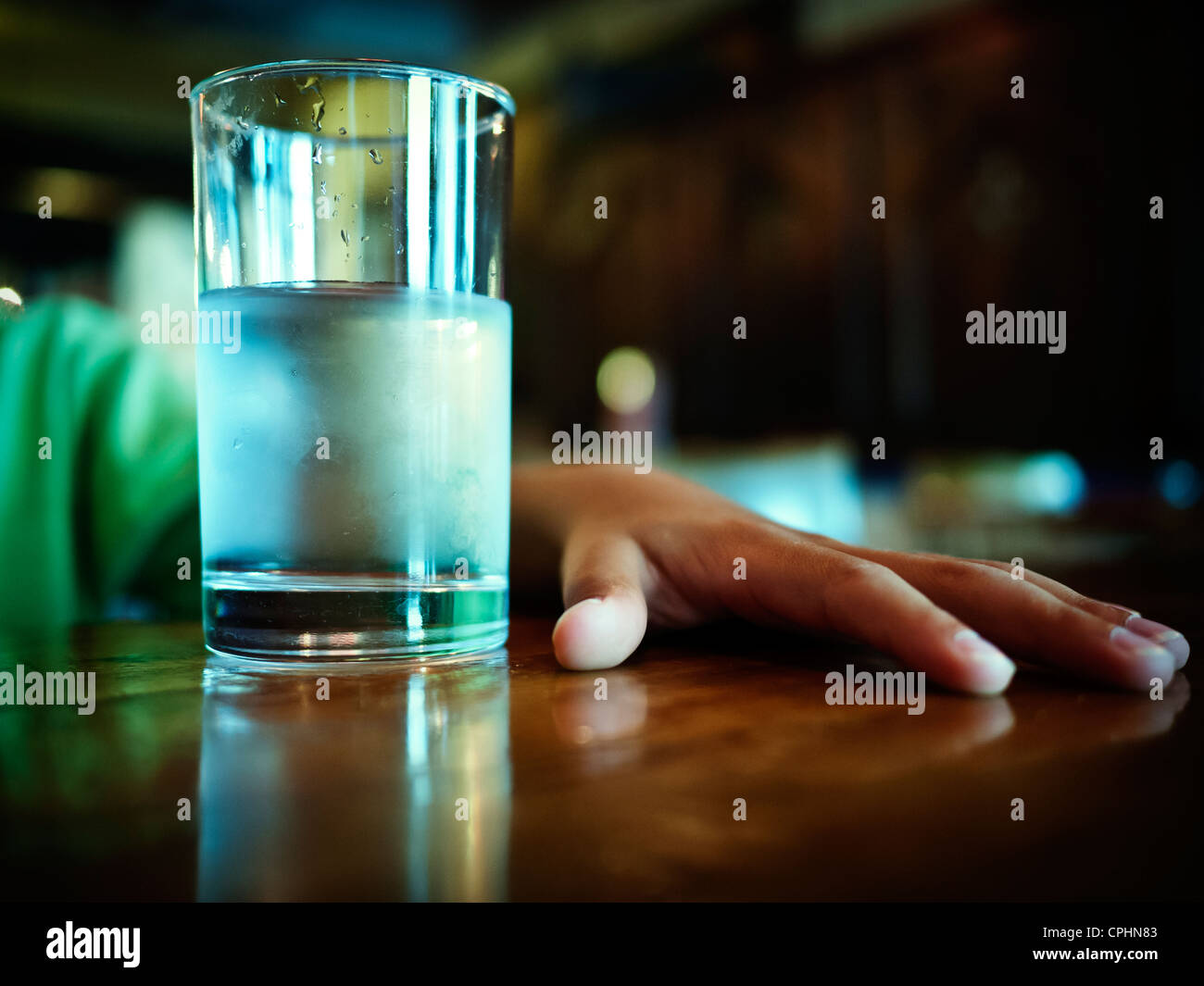 Glass of iced water and boy's hand on table Stock Photo