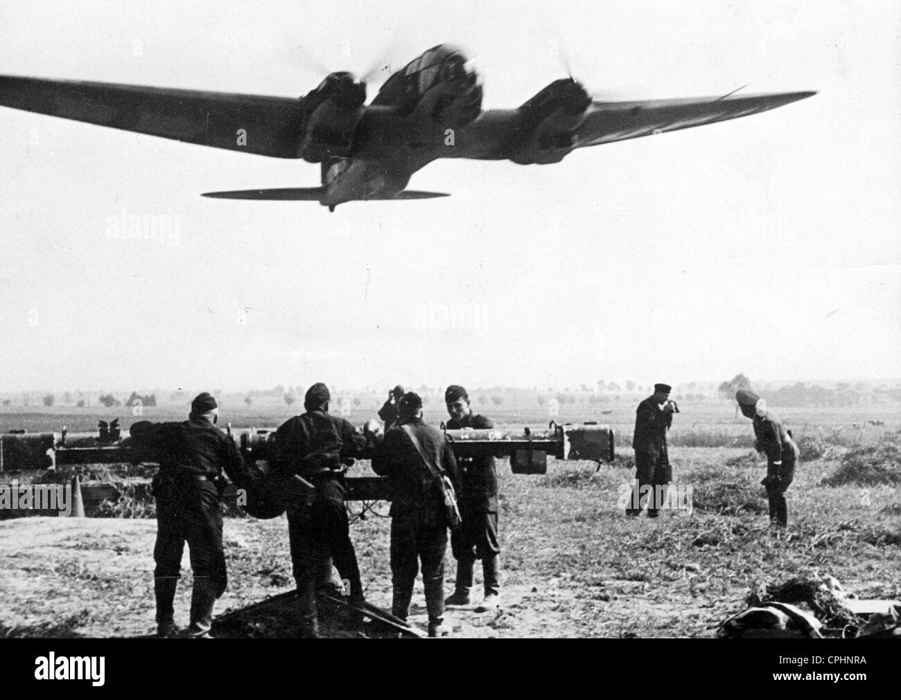 A German plane setting off to attack Poland with soldiers from a flak battery in the foreground, September 1939 (b/w Stock Photo