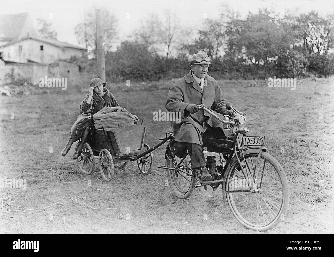 Inflation: A couple from the city transport food purchased in the countryside on a bicycle with an auxiliary engine, 1922 (b/w Stock Photo