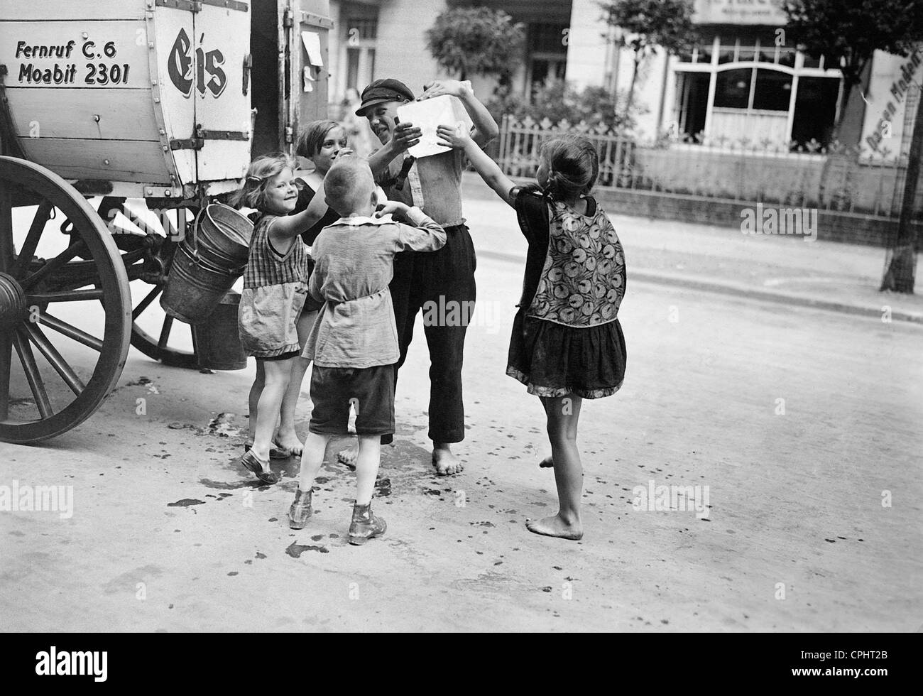 Children surround an ice delivery man, 1929 Stock Photo