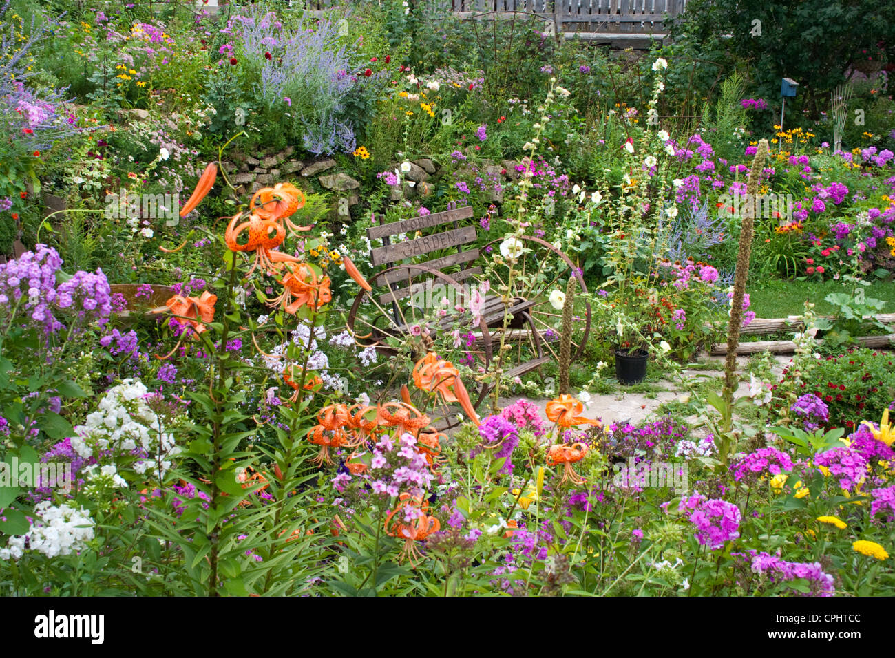 Large flower garden with meditative area containing an antique bench with spoked wheels. Lanesboro Minnesota MN USA Stock Photo