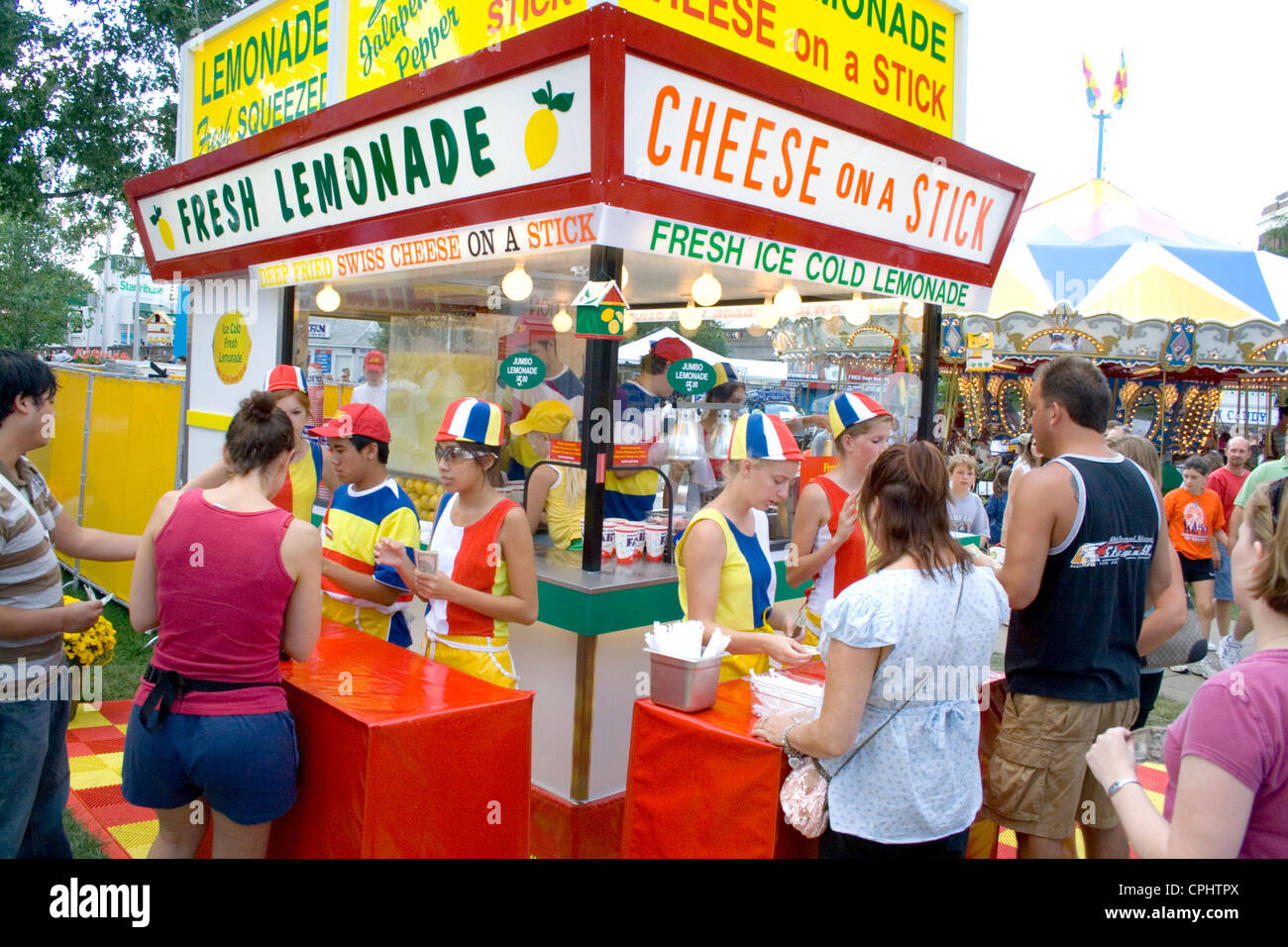Customers buying lemonade and cheese on a stick at a garish concession