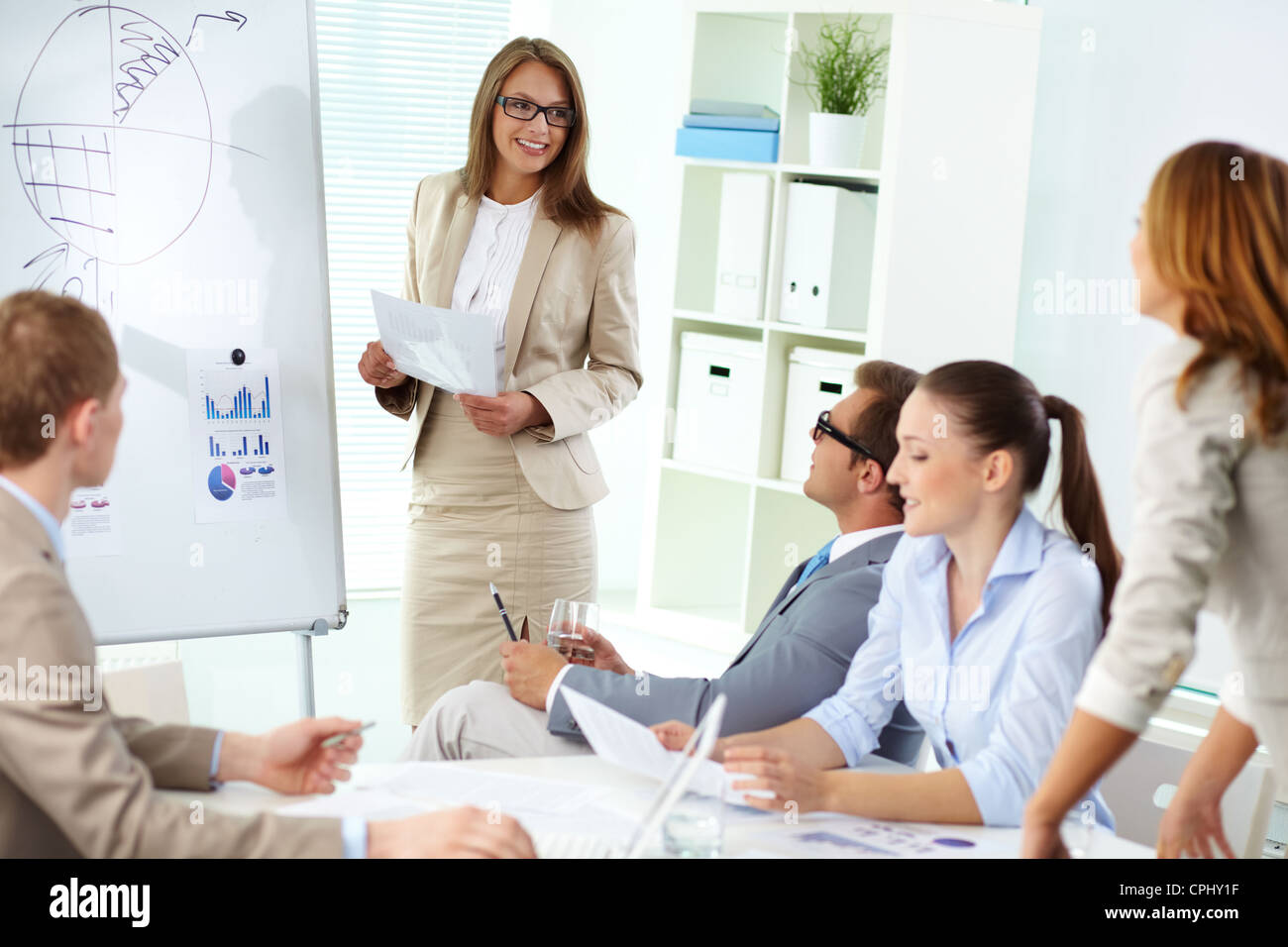 Confident top manager standing by the whiteboard and making report at meeting Stock Photo