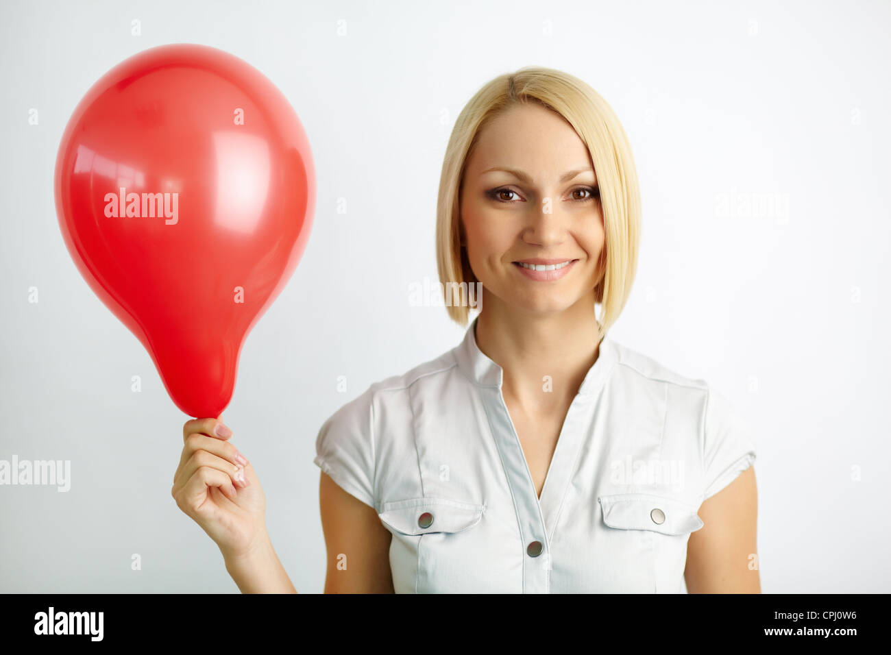 Portrait of a pretty blonde with red balloon smiling at camera Stock Photo