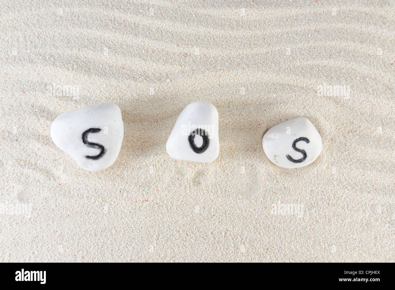 SOS word on group of stones with sand background Stock Photo