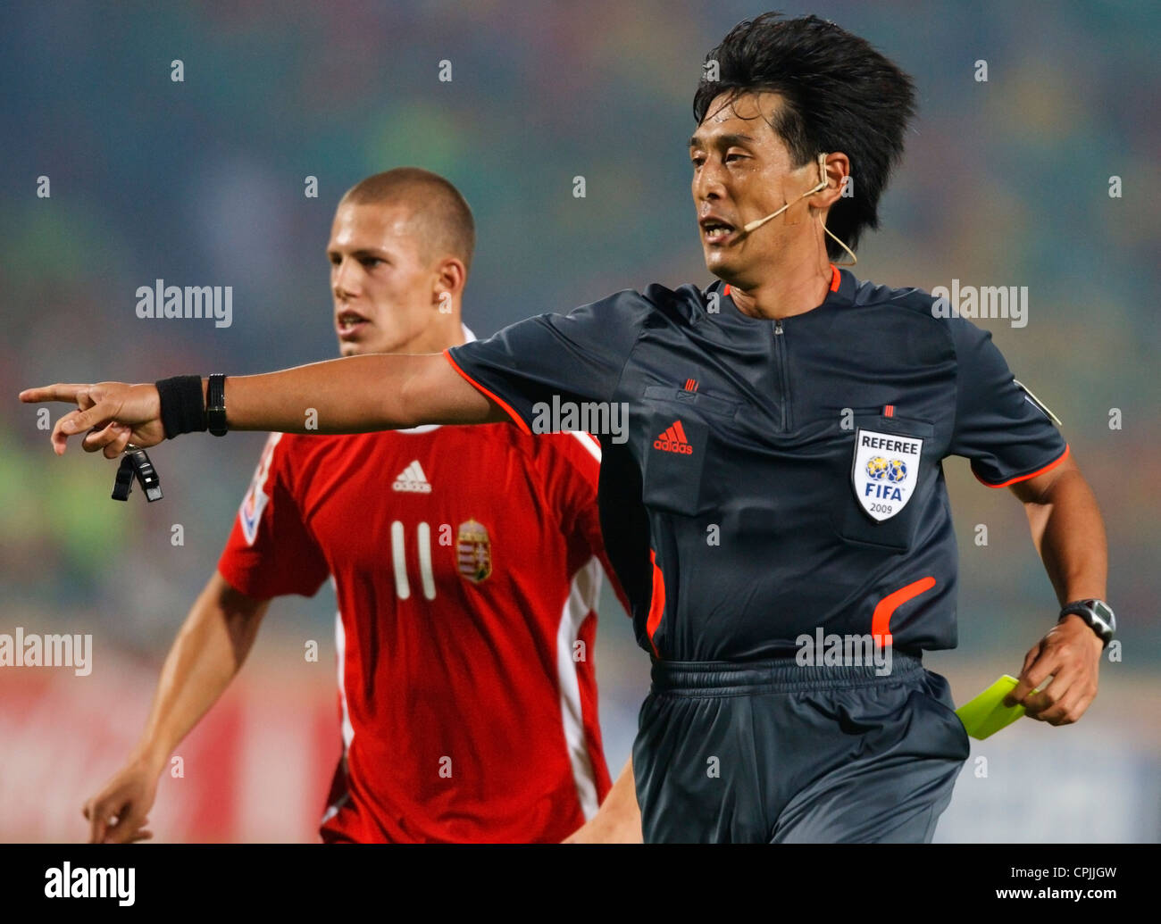 Referee Yuichi Nishimura (Japan) gestures to the penalty spot while pulling out a yellow card during a FIFA U-20 World Cup match Stock Photo