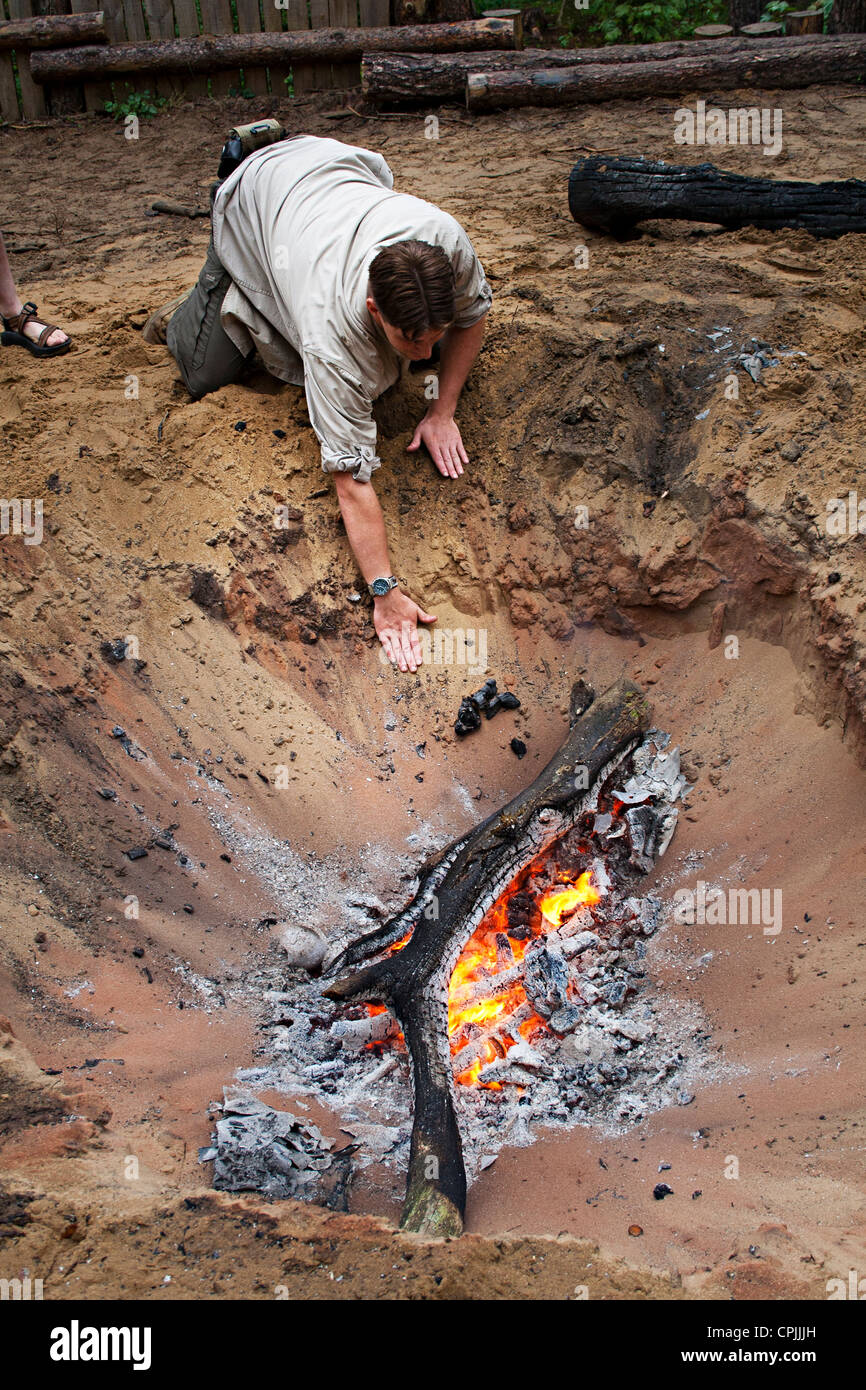 Preparing a roasing pit for bushcraft cooking a pig in sand, Wales, UK Stock Photo