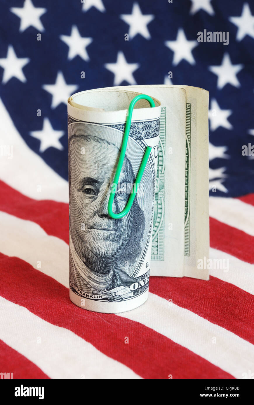 roll of hundred dollars over american flag Stock Photo Alamy