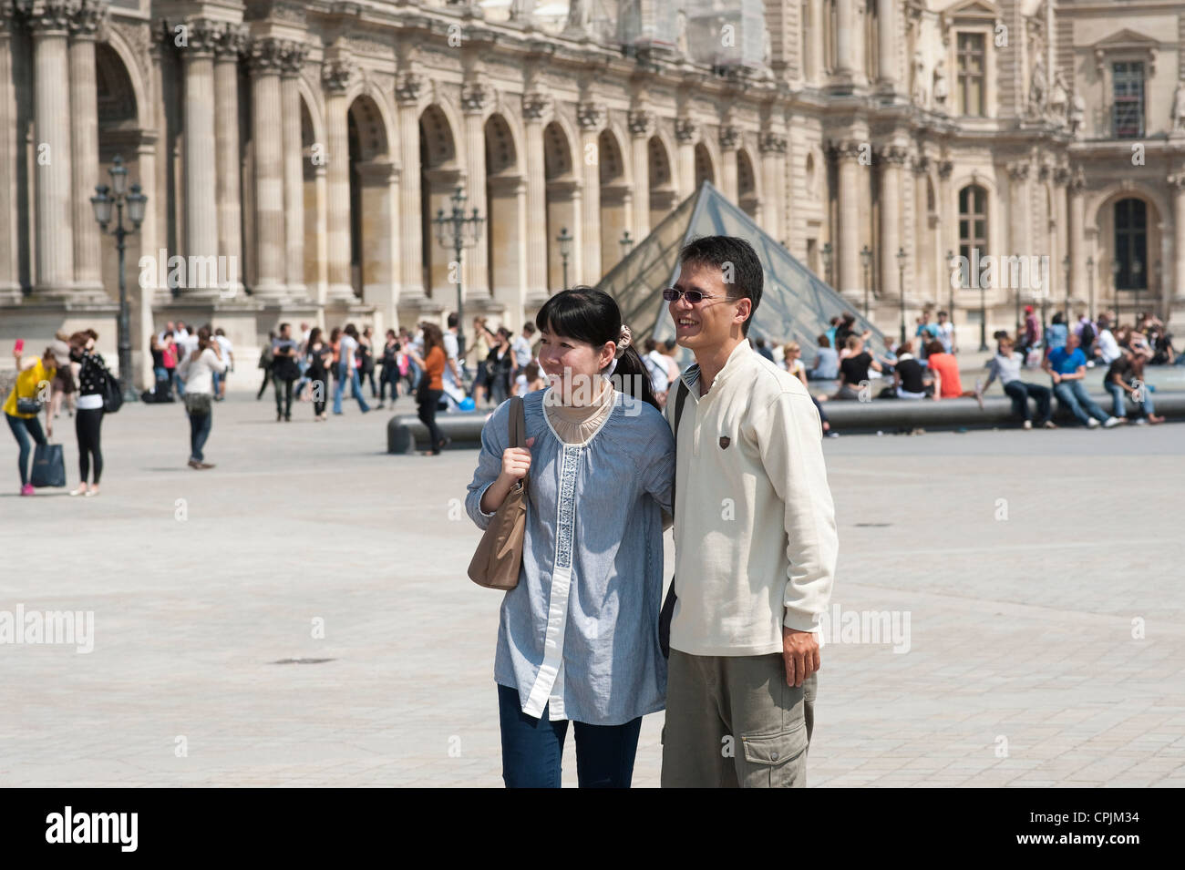 Paris, France - Japanese tourist couple being photographed in front of the Louvre museum. Stock Photo