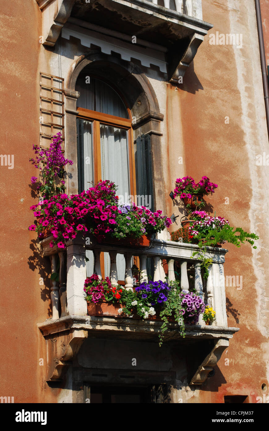 Ancient arched window with balcony and flowers in Venice, Italy Stock