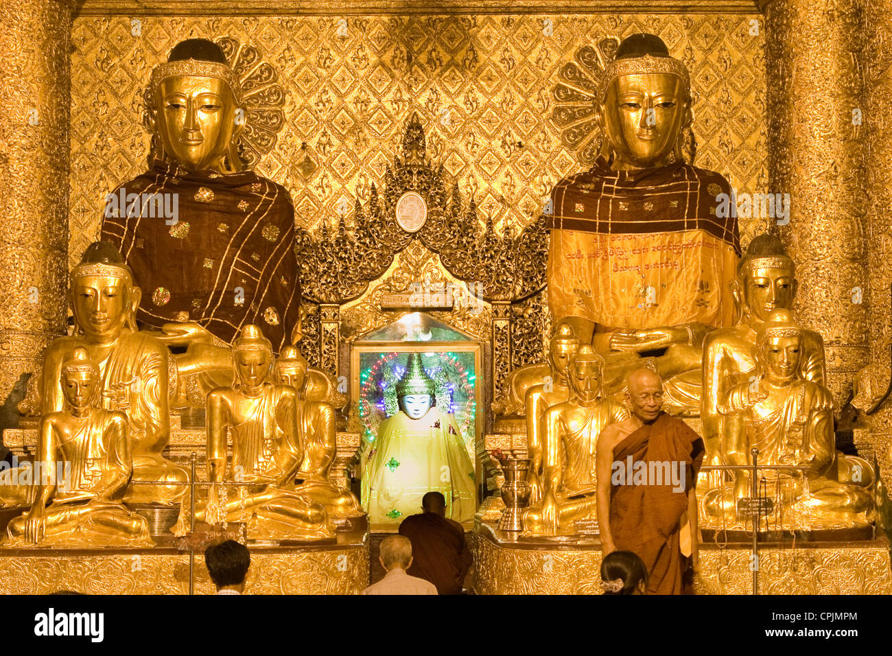 Myanmar, Burma. Shwedagon Pagoda, Yangon, Rangoon. Evening Lights Illuminate Worshipers Praying in a Buddhist Shrine. Stock Photo