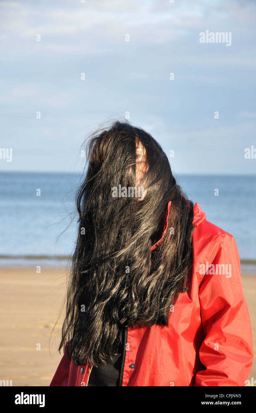 young woman on beach with long brown windswept hair, England, UK Stock Photo