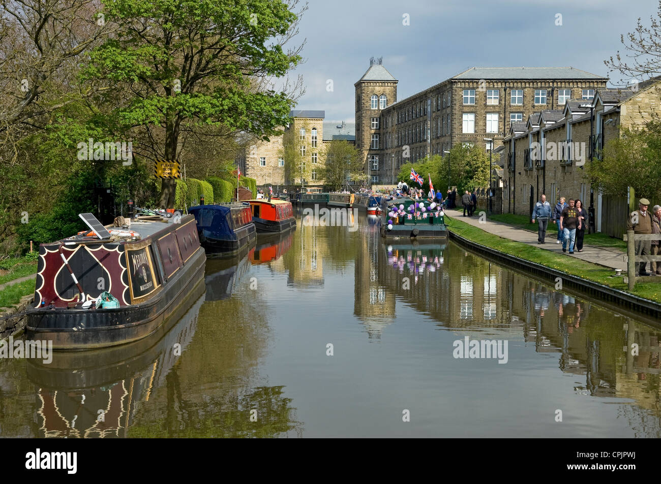 Canal boats barges and people walking on towpath beside Leeds and Liverpool canal waterway near Skipton North Yorkshire England UK GB Britain Stock Photo