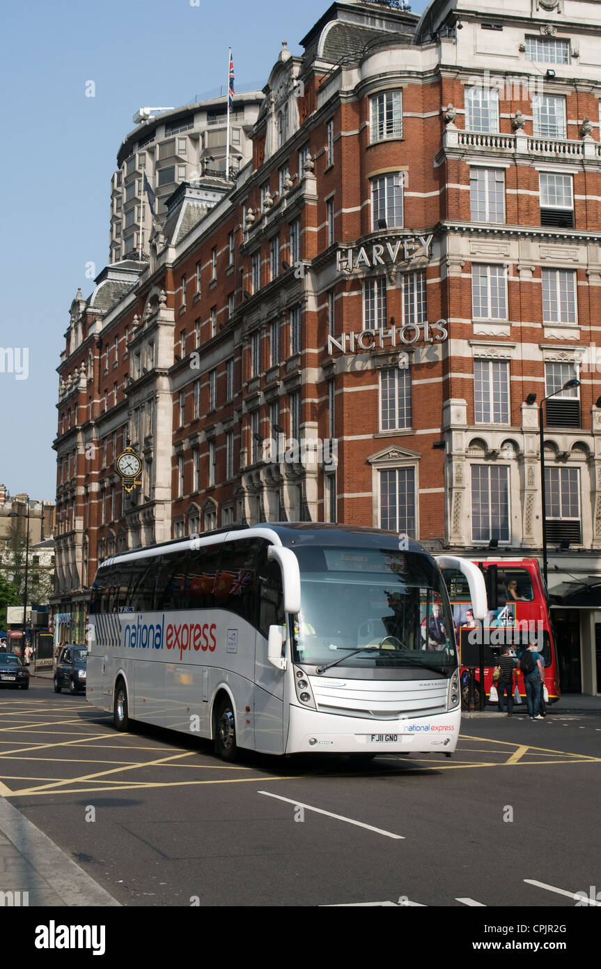 A National Express coach passes Harvey Nichols store in Knightsbridge, London on its way to Swansea, Wales Stock Photo