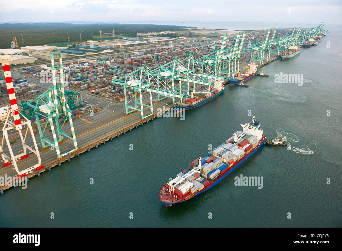 A ship passing by a container terminal shipping port in Johor, Malaysia. Stock Photo
