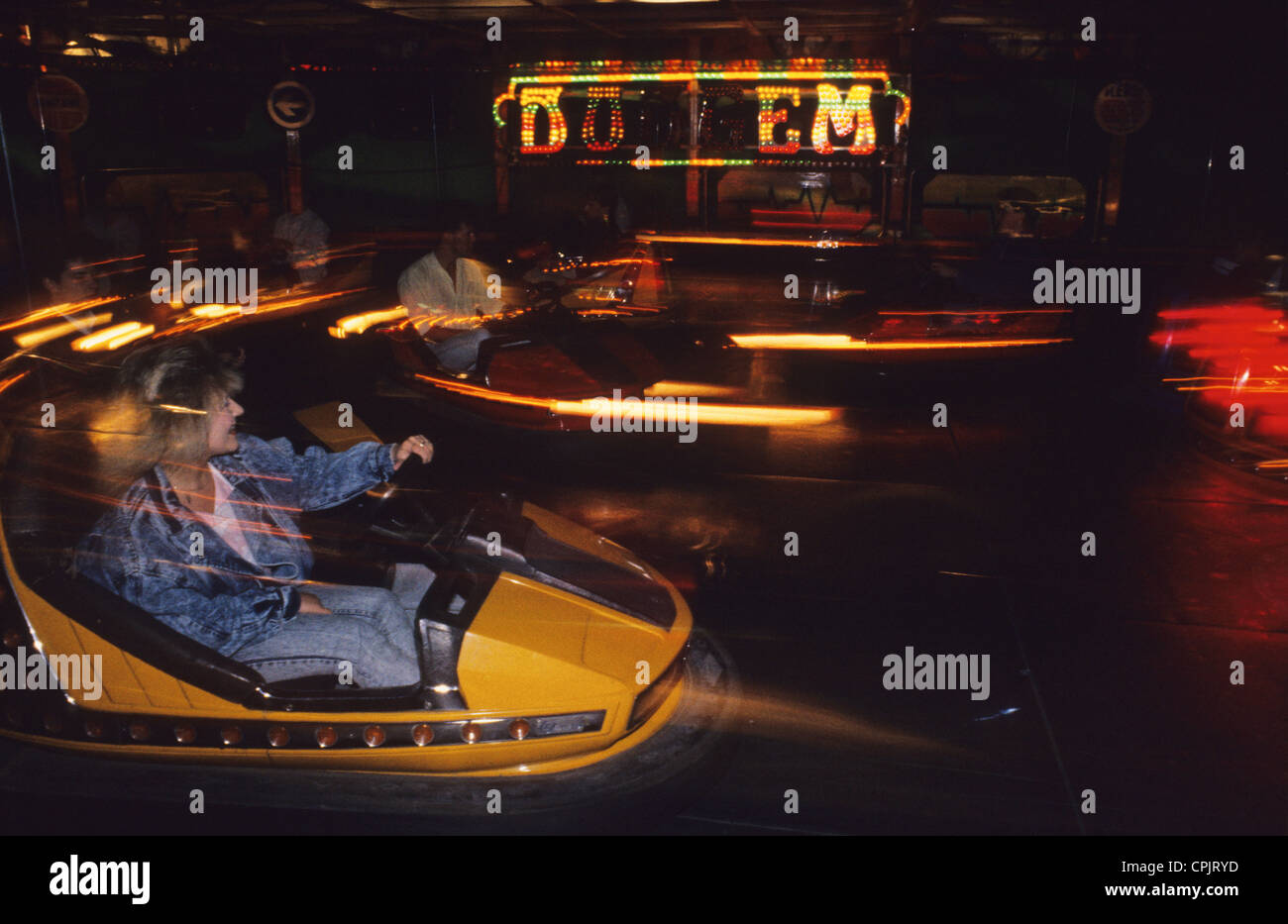 people driving dodgem cars at fairground at night Stock Photo