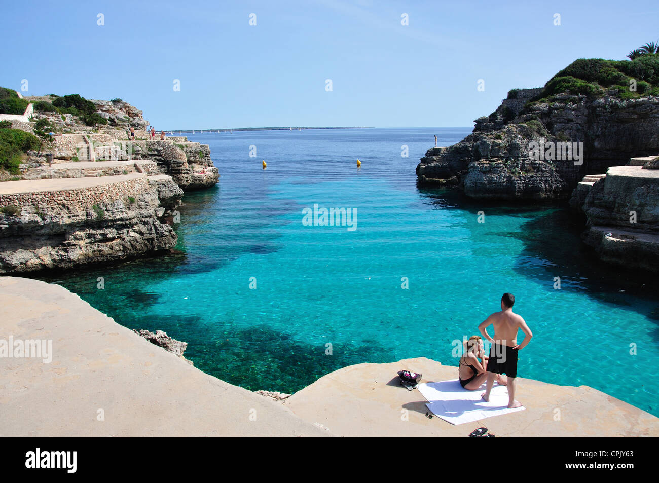 Bathers on rocky ledges, Cala en Forcat, Menorca, Balearic Islands, Spain Stock Photo