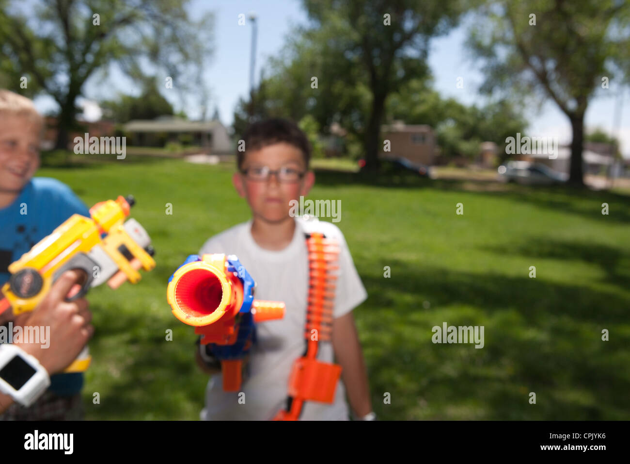 A ten year old boy holding a plastic nerf gun at the camera in a park  during a battle party Stock Photo - Alamy
